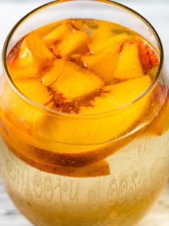 a glass of Peach Sangria with fresh peaches floating on top.