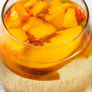 a glass of Peach Sangria with fresh peaches floating on top.