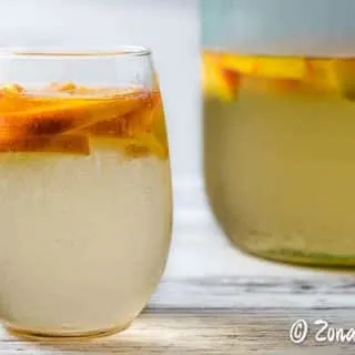 a glass and a pitcher of white peach sangria.