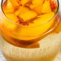 a glass of Peach Sangria with fresh peaches floating on top.