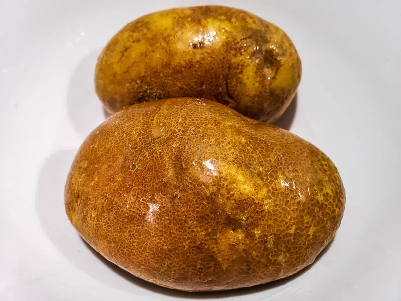 two oiled potatoes in a bowl