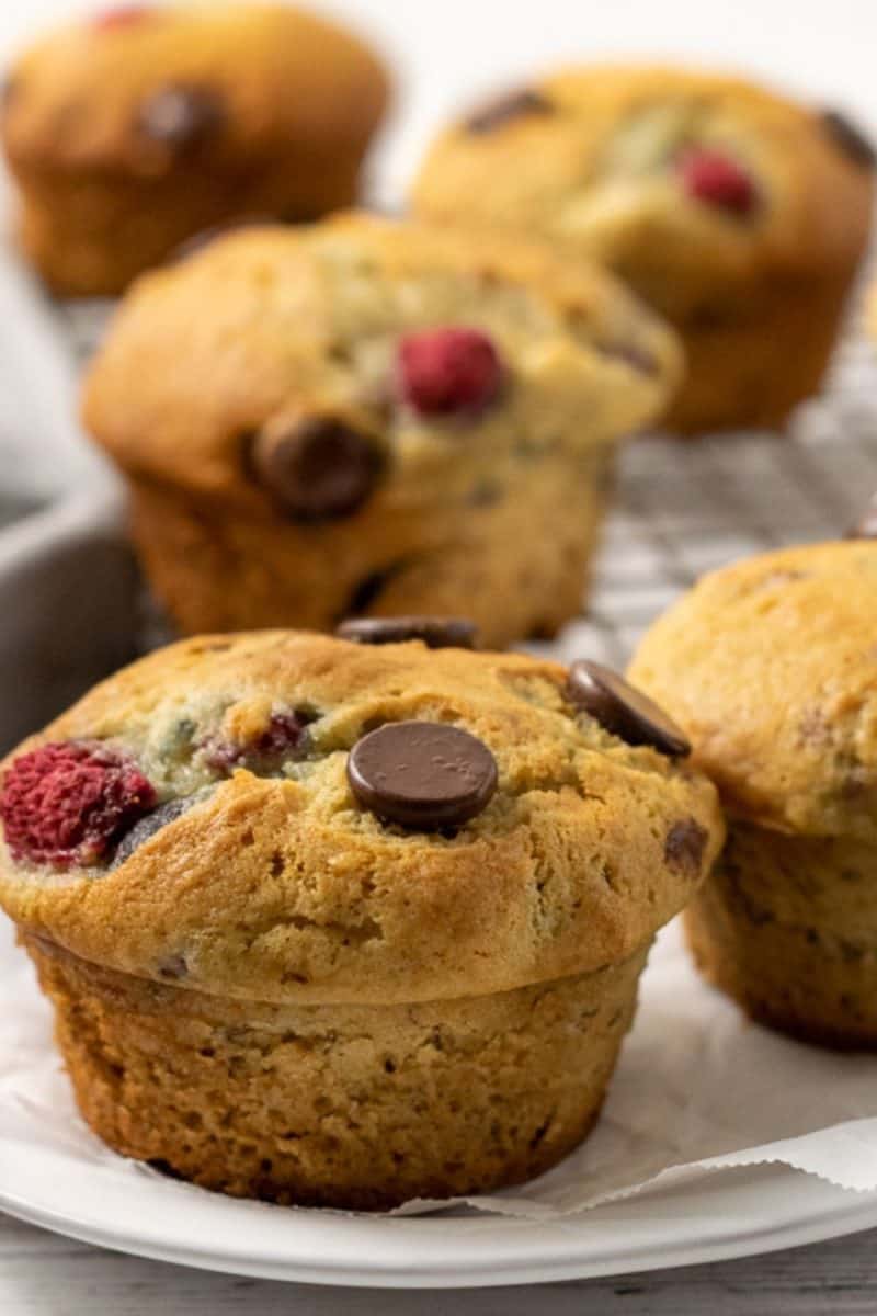 5 Raspberry Dark Chocolate Banana Bread Muffins on a plate and a wire rack.