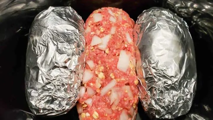 meatloaf and tin foil wrapped potatoes in a crockpot.