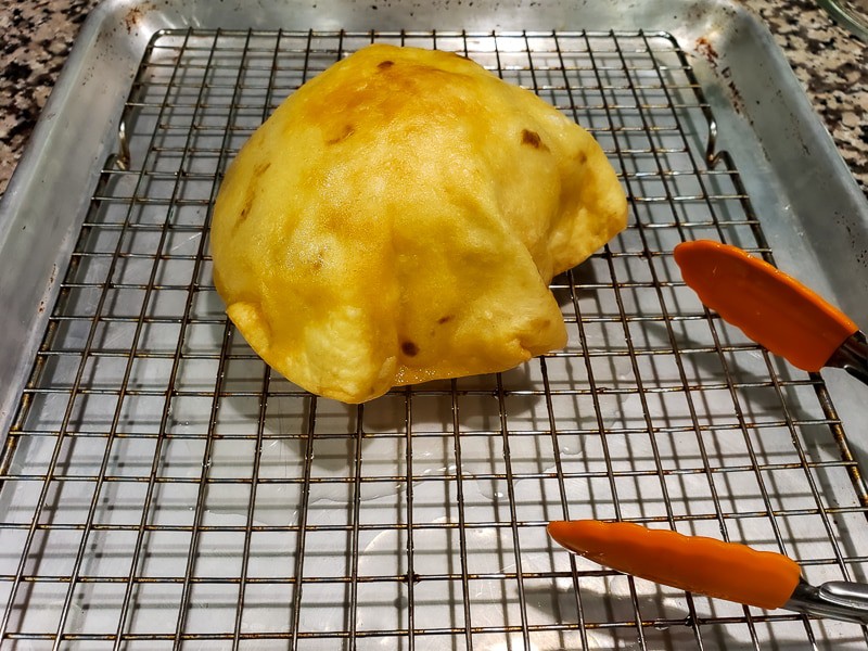 a deep fried tortilla bowl draining upside down on a rack