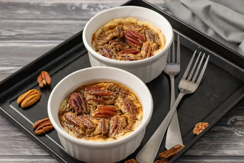 two individual pecan pies on a baking sheet