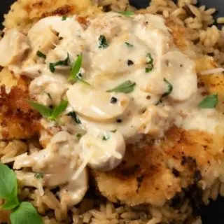 Chicken with Mushroom Parmesan Sauce over rice on a plate.