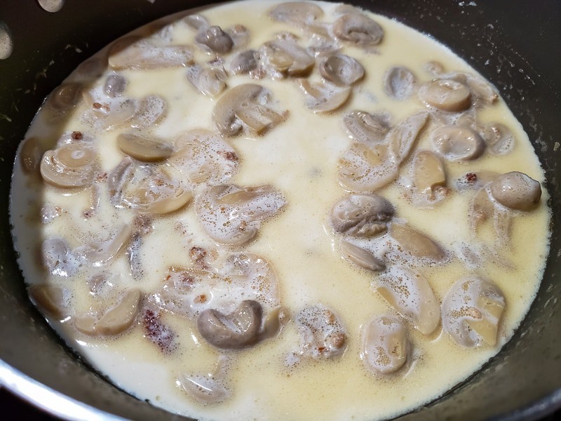 mushrooms, broth, and heavy cream cooking in a pan