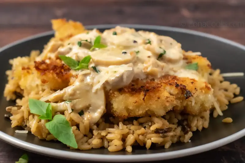 Chicken with Creamy Parmesan Sauce on wild rice on a plate.