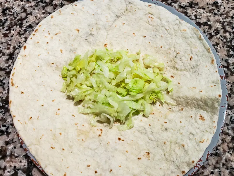 shredded lettuce on a burrito tortilla