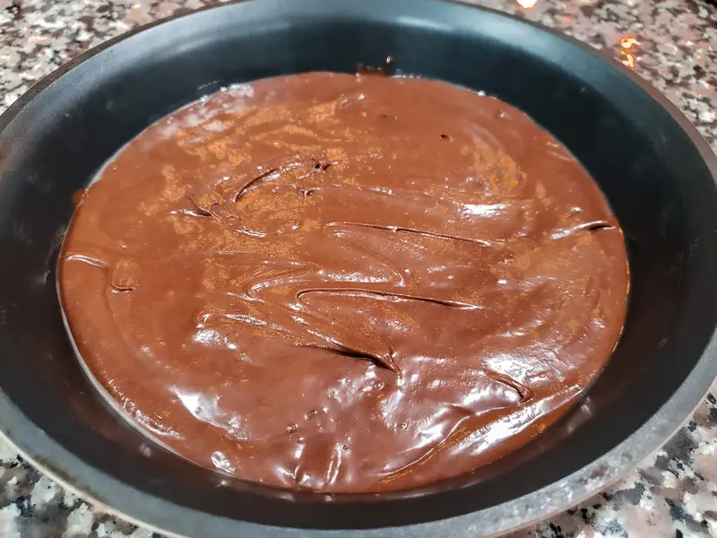 brownie batter poured into a buttered pie dish.