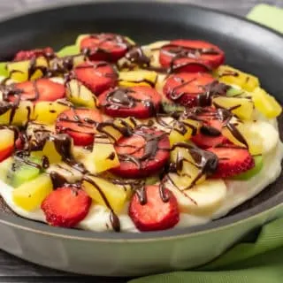 fruity brownie pizza drizzled with chocolate.