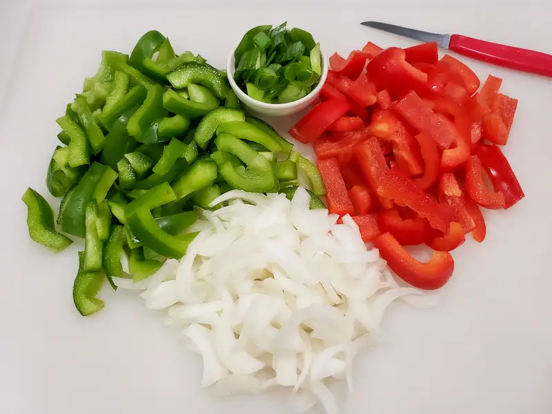 green pepper, red pepper, onion, green onion diced on a cutting board