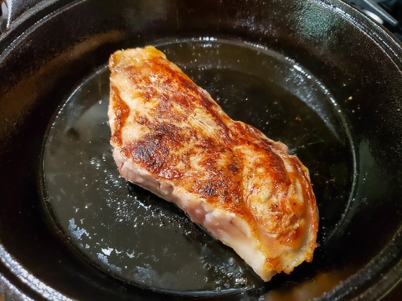 strip steak frying in a skillet