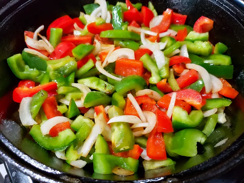 onions, green pepper, red pepper cooking in a skillet