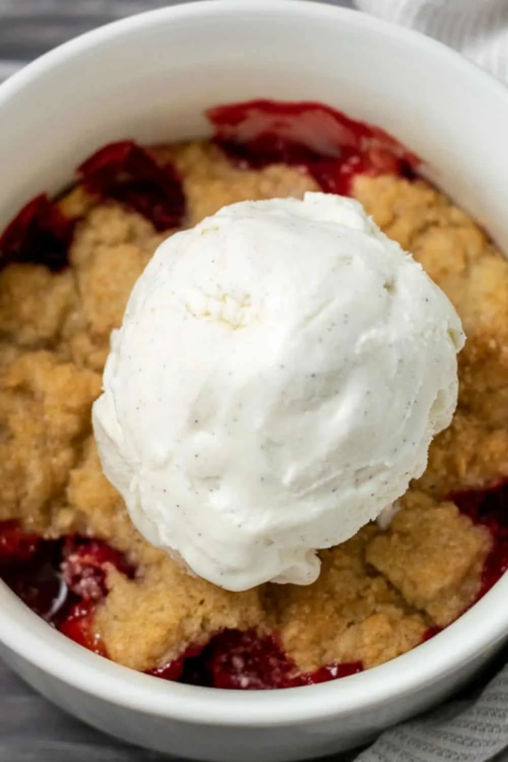 Cakey Strawberry Cobbler topped with vanilla bean ice cream.