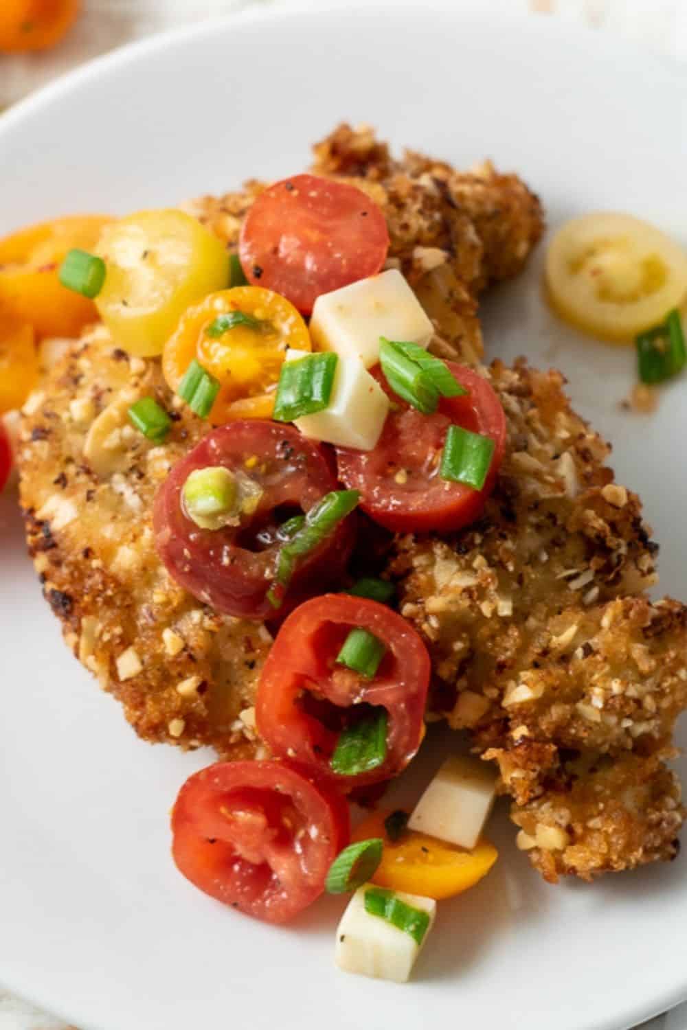 Almond Panko Chicken with Italian Tomato Salad on a plate.