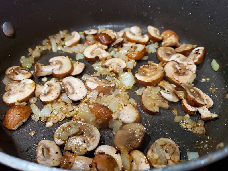 mushrooms, onions, and garlic cooking in a pan.
