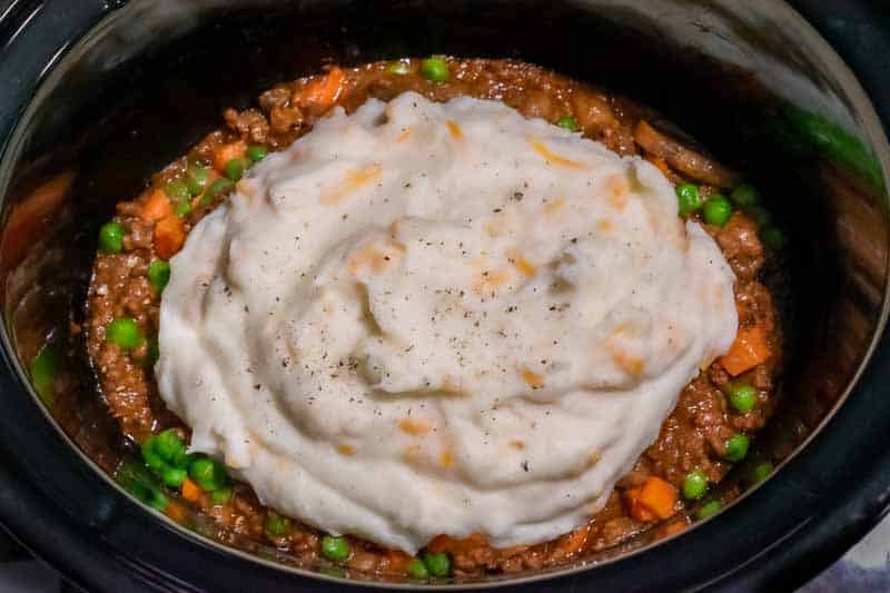 mashed potatoes on top of the shepherd's pie in a crockpot.