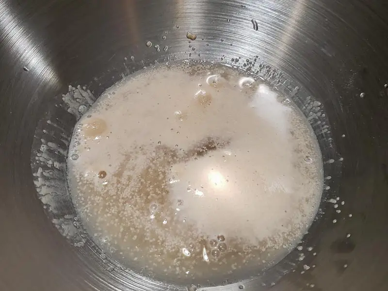 yeast, water, and sugar getting frothy in a bowl