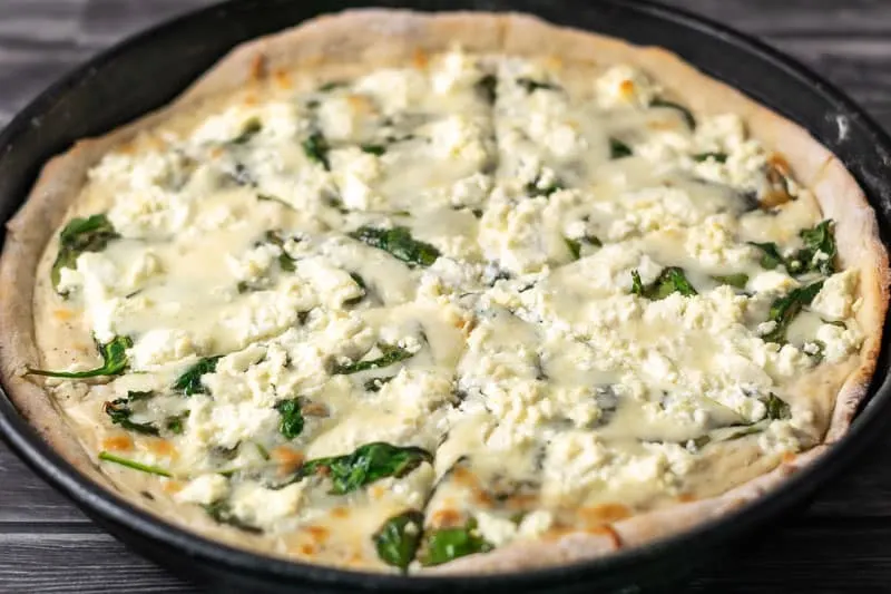 Goat Cheese Spinach Pizza cut into slices.
