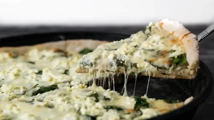lifting out one slice of Goat Cheese and Spinach Pizza