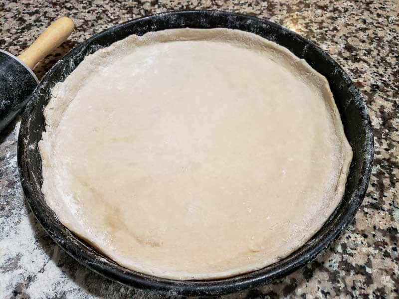 pizza dough pressed into pizza pan