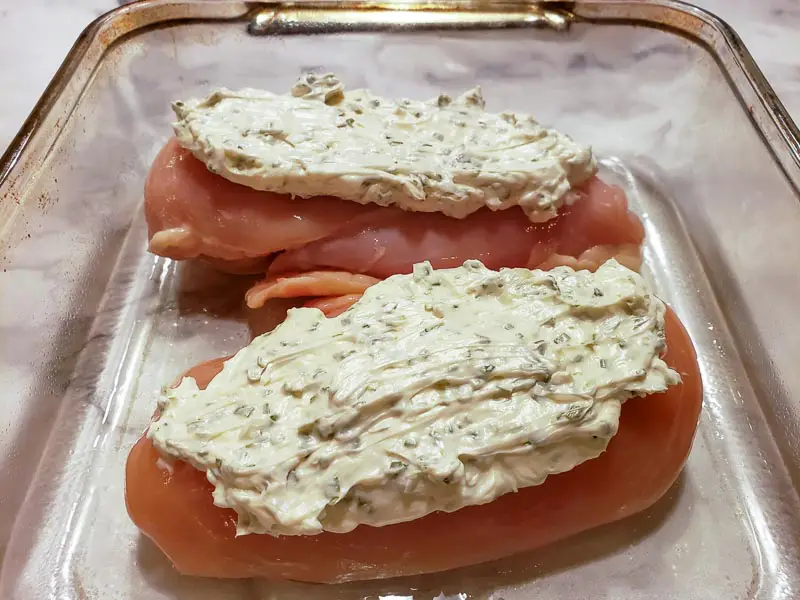 cream cheese and chives spread over two pieces of chicken.