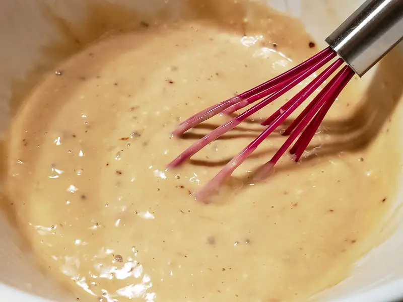 apple cider gravy with a whisk in a bowl.
