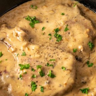 One Skillet Pork Chops and Apple Cider Gravy in a cast iron skillet.