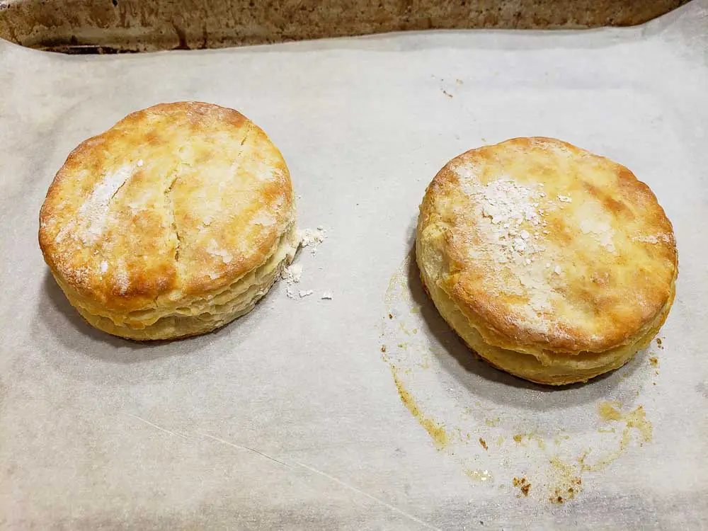 two homemade buttermilk biscuits on a baking sheet.