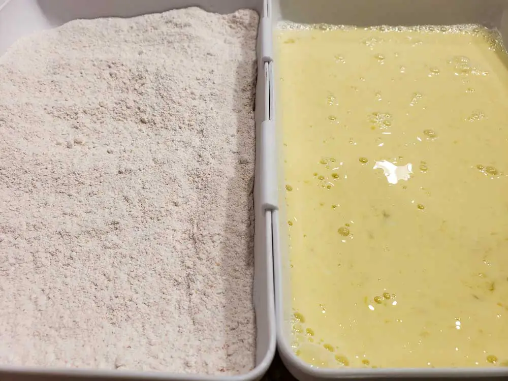 flour and seasoning mixture in tray on left and egg, milk, and vinegar mixture in tray on right.
