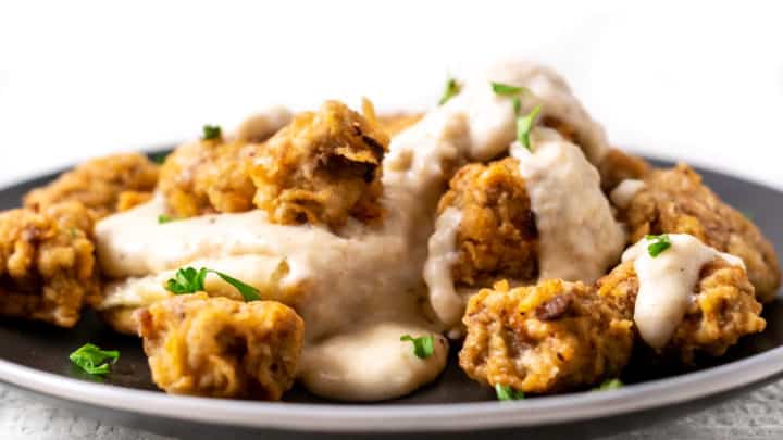 close up view of Chicken Fried Steak Bites and Pepper Gravy with Homemade Biscuits on a plate
