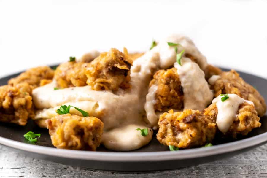 close up view of Chicken Fried Steak Bites and Pepper Gravy with Homemade Biscuits on a plate
