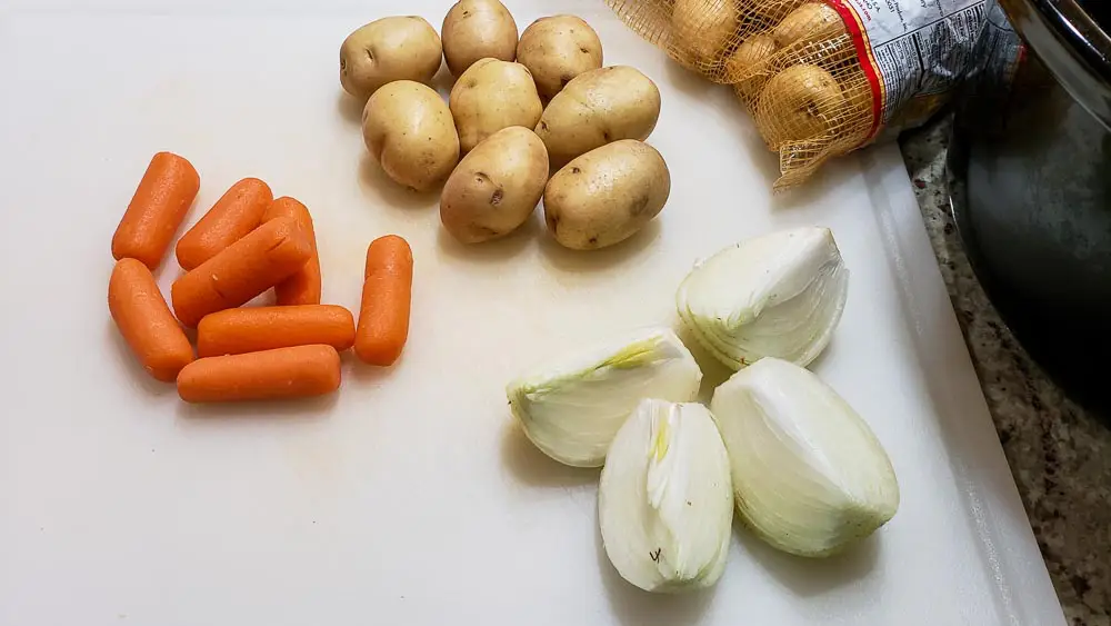 baby carrots, baby potatoes, and an onion cut into quarters