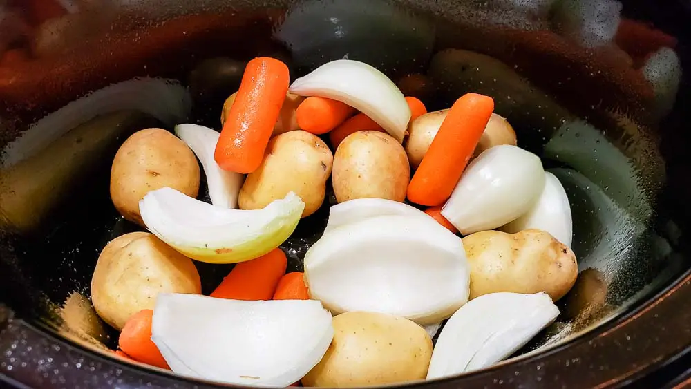 onion, potatoes, and carrots in a slow cooker crock pot