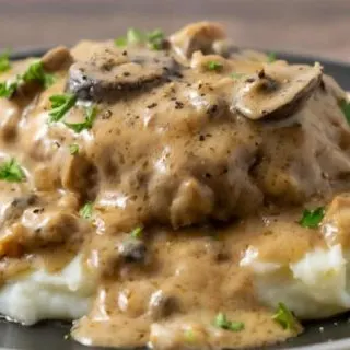 Salisbury Steak and Mushroom Gravy over mashed potatoes on a plate.