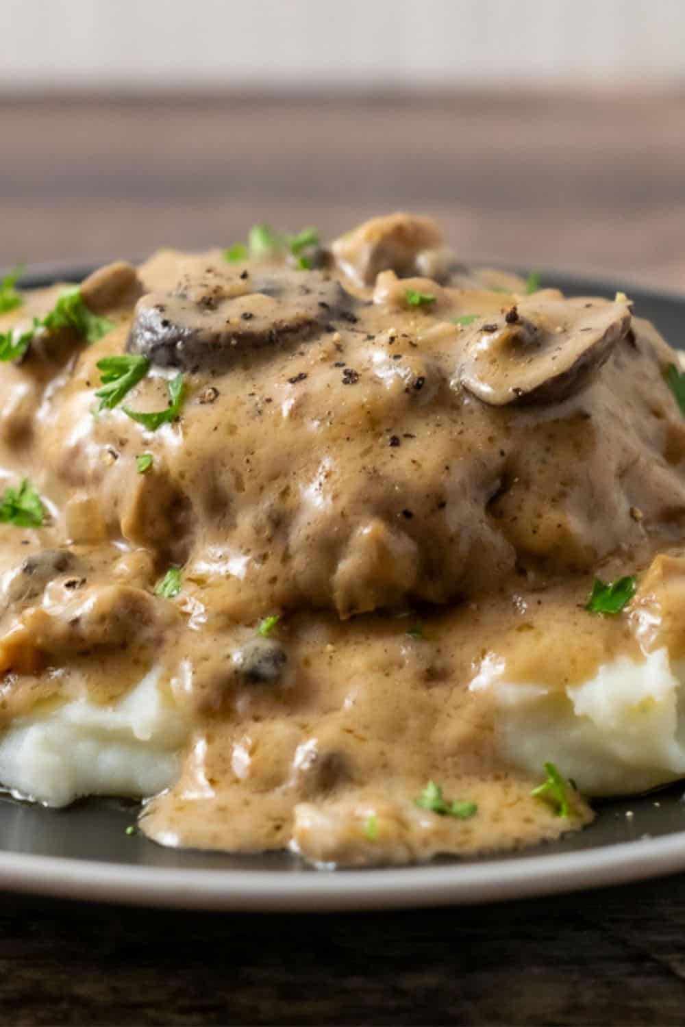 Salisbury Steak and Mushroom Gravy over mashed potatoes on a plate.