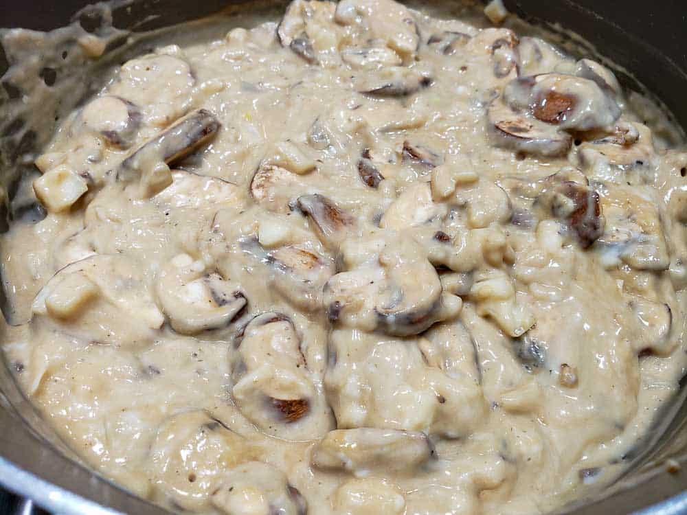 cream of mushroom soup, beef bouillon water mixture, Worcestershire, mushrooms, and onion mixed together in a frying pan.