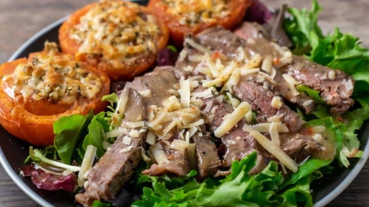 salad greens topped with steak, parmesan cheese, and dressing with 3 parm broiled tomatoes