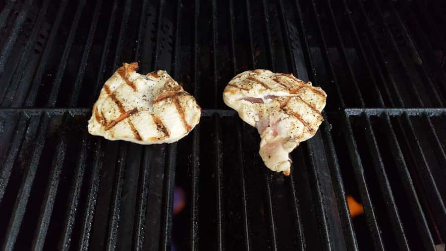 two chicken filets cooking on a grill