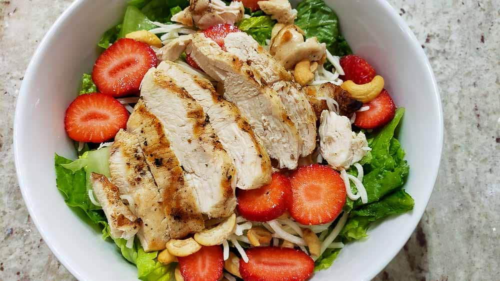grilled chicken layered on top of strawberry salad.