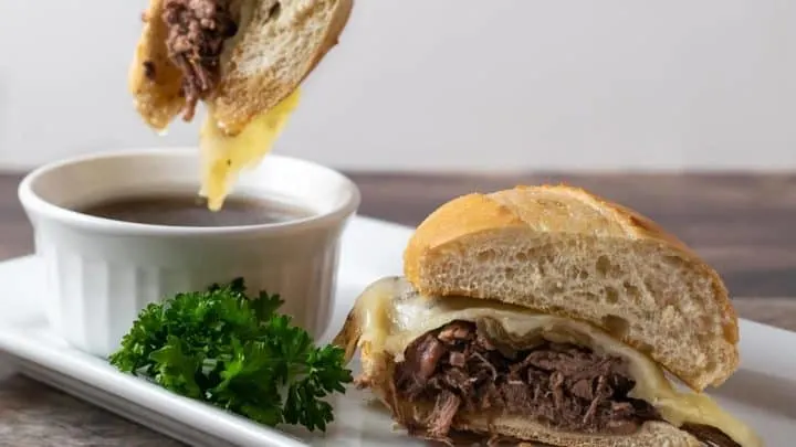Crockpot French Dip Sandwich dipping into Au Jus