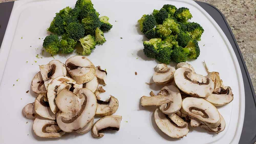 chopped broccoli and mushrooms on a cutting board.