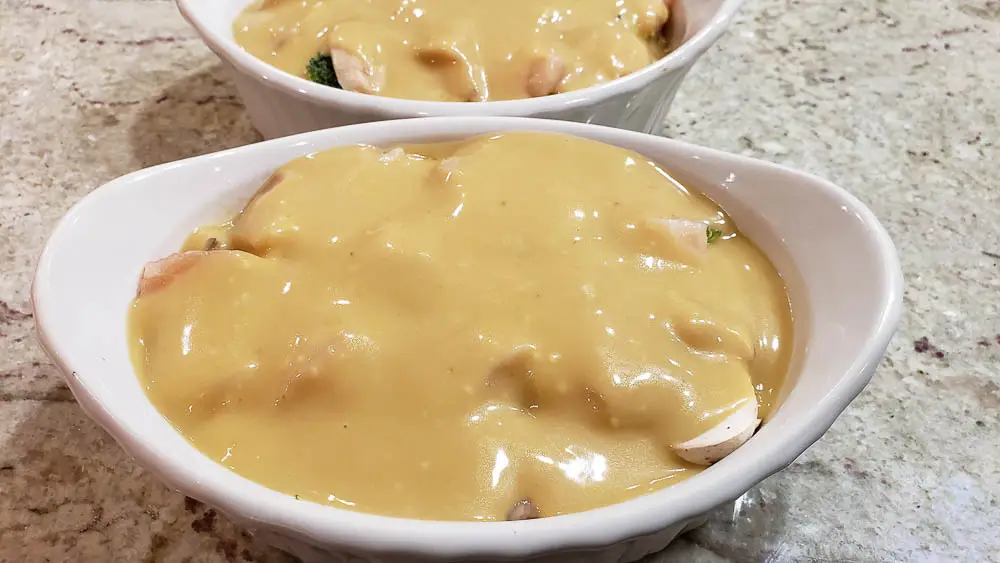 Creamy Mushroom Chicken and Rice with soup mixture layered over chicken in two dishes.