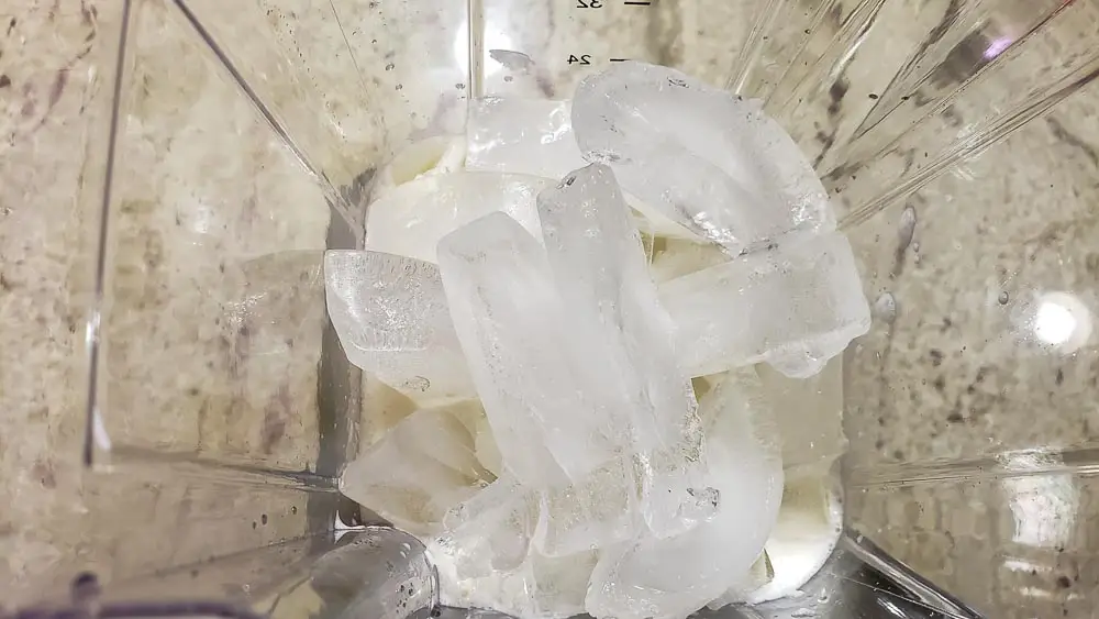 ice cubes, coconut cream, and pineapple juice in a blender