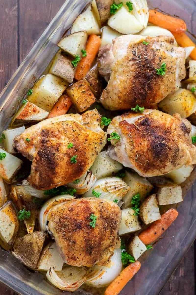 Baked Chicken Thighs with Potatoes and Carrots in a casserole dish.
