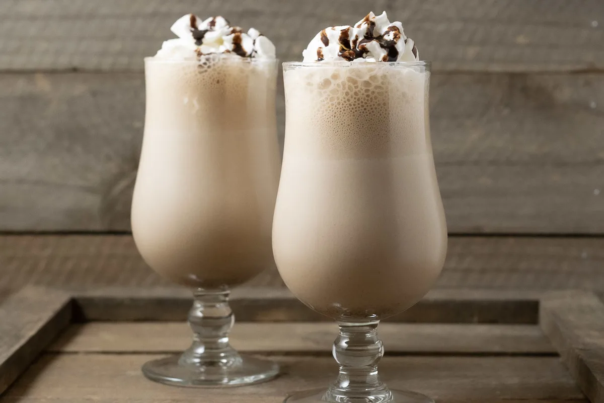 two Arby's Copycat Jamocha Shakes topped with whipped cream and chocolate drizzle.
