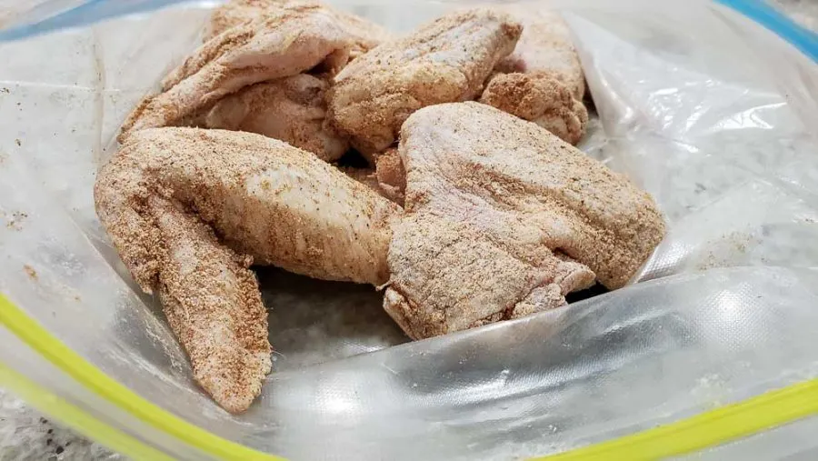 raw chicken wings coated with seasonings in a zipper baggie.