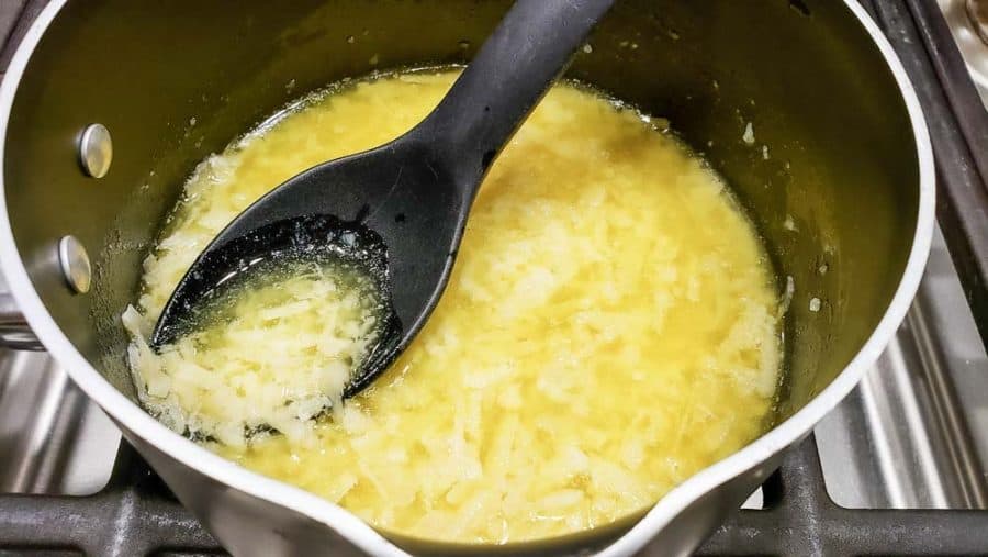 melted butter, parmesan cheese, and garlic in a sauce pan with a spoon.