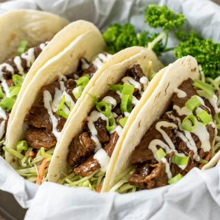 four Korean BBQ Tacos in a paper lined basket with parsley